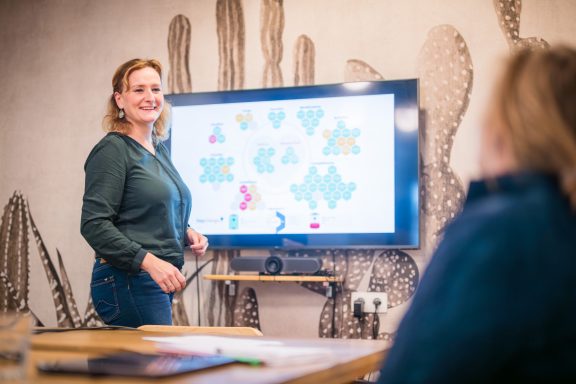 Femme présentant des graphiques colorés lors d'une réunion dans une salle moderne.