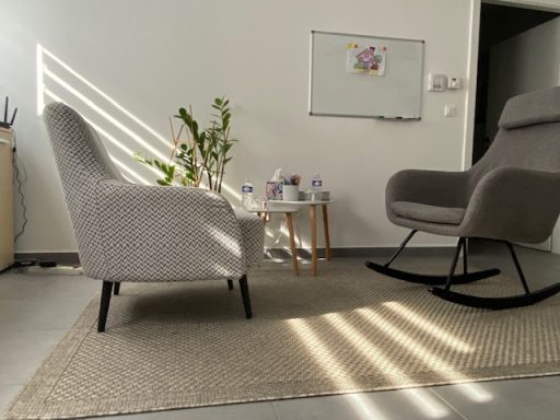 Chaises confortables et table basse dans un salon lumineux avec des rayons de soleil.